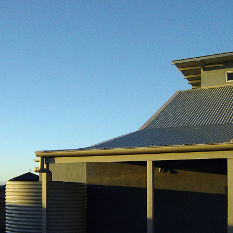 traditional vernacular roof forms and watertanks in a clever suburban house